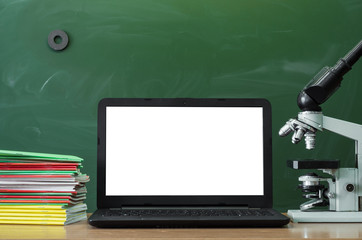 Teacher or student desk table. Education background. Education concept. Laptop with blank screen, microscope and stacked books on the table.