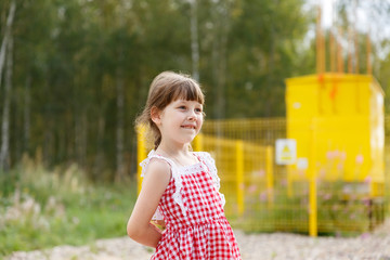 Naklejka premium 6-year-old girl looks with curiosity, biting her lip