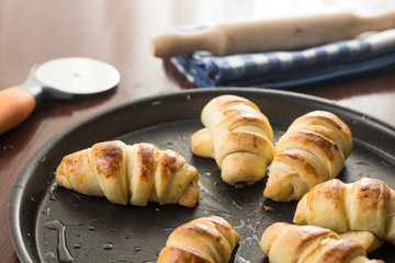 Baked bun rolls on the baking tray with utensils in the background