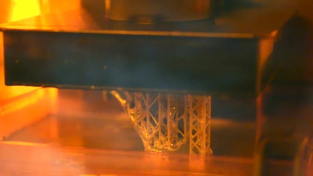 Stereolithography DPL 3d printer create detail and liquid drips, platform slowly move with liquid close-up. Progressive modern additive technology 3D printing, create scaled model by UV polymerization