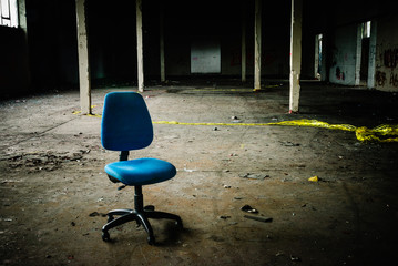 Office chair sits in the middle of an empty, abandoned warehouse.