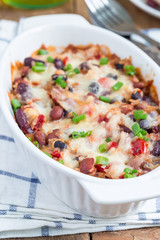 Baked rice casserole with different kinds of beans, cheese and paprika, in white ceramic baking dish, vertical