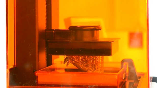 Stereolithography DPL 3d printer create detail and liquid drips, platform slowly move with liquid close-up. Progressive modern additive technology 3D printing, create scaled model by UV polymerization