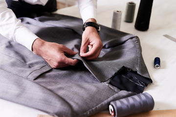 Production process of custom-made male jacket: unrecognizable tailor concentrated on sewing with...