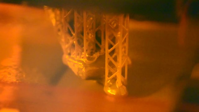 Stereolithography DPL 3d printer create detail and liquid drips, platform slowly move with liquid close-up. Progressive modern additive technology 3D printing, create scaled model by UV polymerization