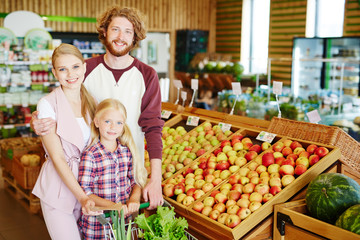 Family of young husband and wife and their daughter shopping in supermarket