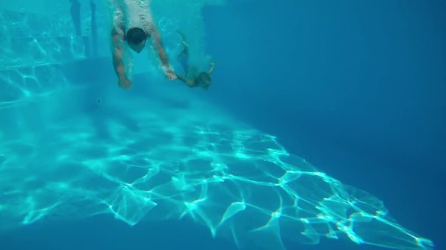 Underwater swimming.
Father and son swimming together under water in swimming pool.