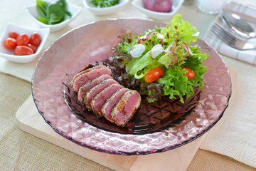 Tuna salad with glass plate on wood cutting board.