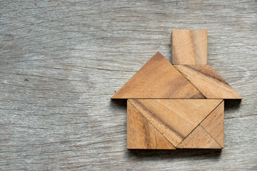 Tangram puzzle in home shape on wood background