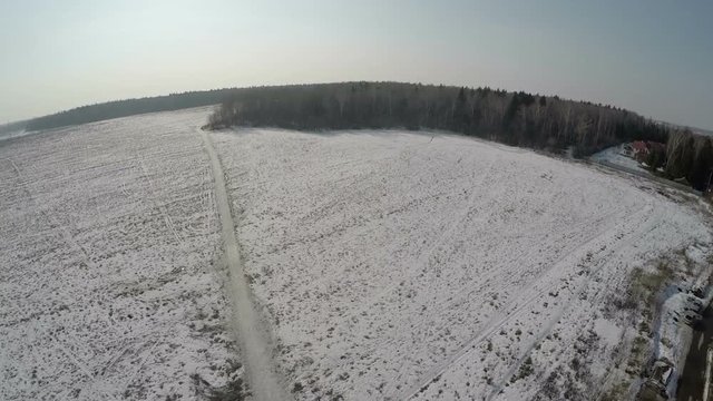 Copter rising and opening aerial panorama to vast snowy fields, forests and small town