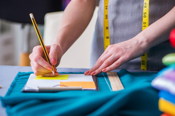 Woman tailor working on a clothing sewing stitching measuring fa