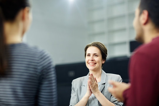 Happy middle-aged businesswoman with her palms put together listening to co-worker or subordinate
