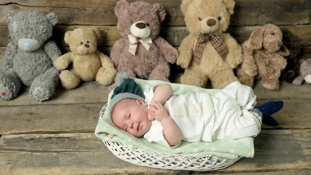 Sleepy baby in a basket. Small child and teddybears.
