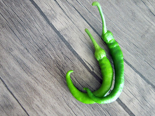 two green long pepper on a wooden floor, vegetables