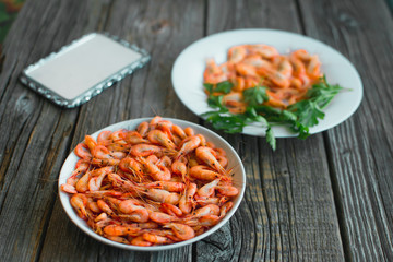 on a wooden background, white plate with shrimps