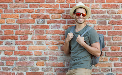 Сloseup portrait of sporty tourist man pictured against red brick background on summer day wearing...