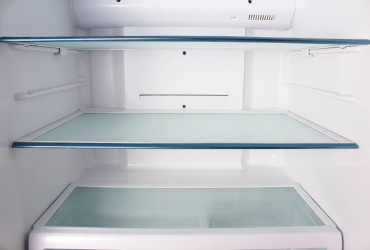Inside the empty white refrigerator with shelves for where to place bottles of water, fruit , food ,
