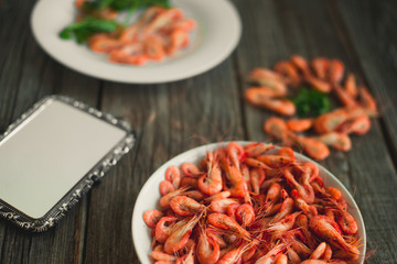 on a wooden background, white plate with shrimps
