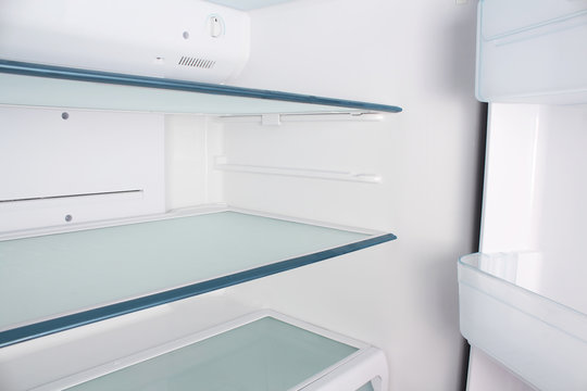 Inside the empty white refrigerator with shelves for where to place bottles of water, fruit , food ,