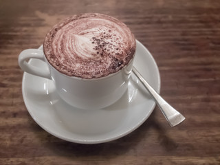 close up of a delicious cup of coffee on wooden table.