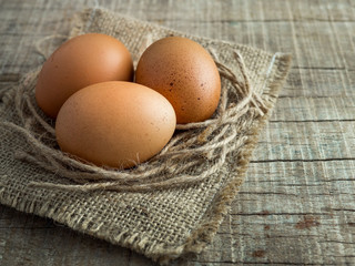3 eggs on a old sack with rope on wooden background, eggs with vintage tone