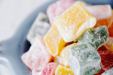 sweets and desserts, macro food, multi-colored oriental rahat tortoise, Turkish delight  in powdered sugar on a light background