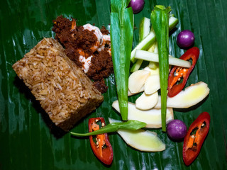 Shrimp chili dip fried rice with fresh vegetable served on banana leaf.