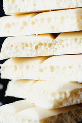 sweets and desserts, macro food, milky white  porous chocolate  on a dark background