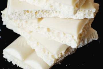 sweets and desserts, macro food, milky white  porous chocolate  on a dark background