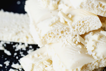 sweets and desserts, macro food, milky white  porous chocolate  on a dark background