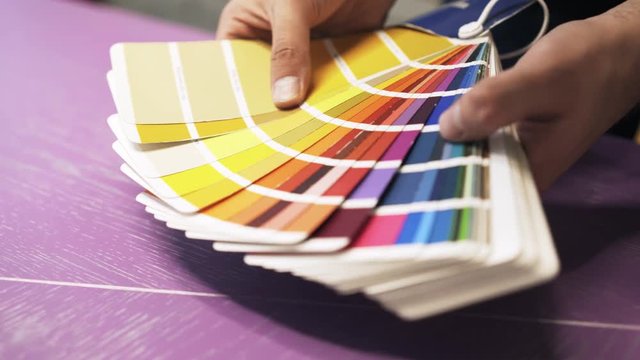 Close up of hands of an unrecognizable man holding a color chart and looking at it. Handheld real time close up shot