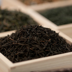 Dry black tea in a wooden display case with other types of tea