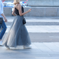 Fototapeta na wymiar stylish girl in a fluffy airy skirt walk a quick step on the summer city