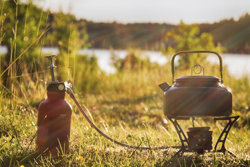 Campingkocher auf einer Wiese am See, Gegenlicht