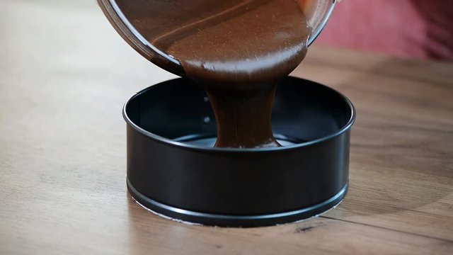 Pouring cake mix into baking tin, springform . Making chocolate Cake.