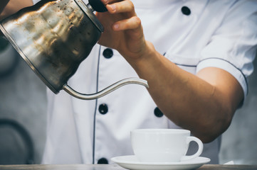 Barista pour milk to coffee cup in coffee shop
