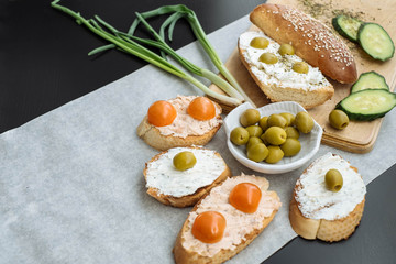 Bruschetta with soft cream cheese, olives and cherry tomatoes. Vegetarian breakfast with space for text