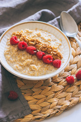Morning breakfast, oatmeal in milk with raspberries and walnuts