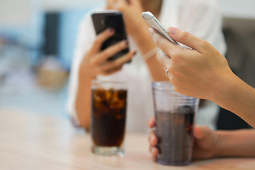 close up man hand holding smartphone for playing or surfing on internet with friends in restaurant while waiting food,city life-style concept