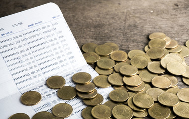 Saving money with gold coin stack and book bank on wood table for investment, business and...