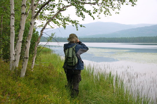 Traveler taking pictures of a forest lake.