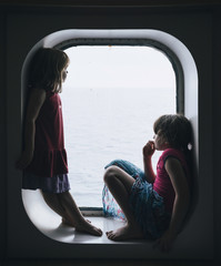 Two little girls looking from a cruise window