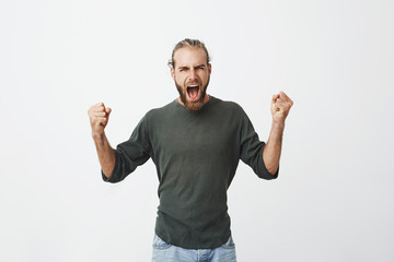 Happy attractive man with beard screaming loudly and expressive gesticulating with hands when his...