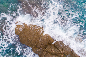 Fototapeta na wymiar A bird's-eye view of how turquoise waves beat about sea cliffs in Montenegro