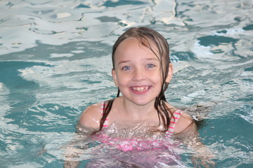 Young girl-child, playing in and, having fun in a swimming pool.

