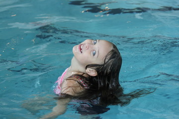 Young girl-child, playing in and, having fun in a swimming pool.

