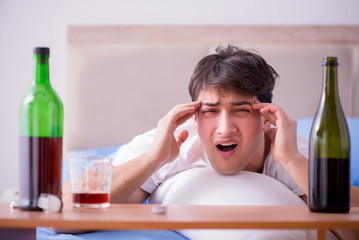 Man alcoholic drinking in bed going through break up depression