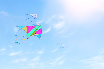 Fototapeta na wymiar Colorful kite flying in the blue sky through the clouds