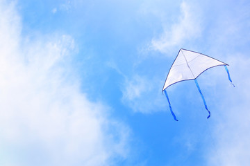 Colorful kite flying in the blue sky through the clouds