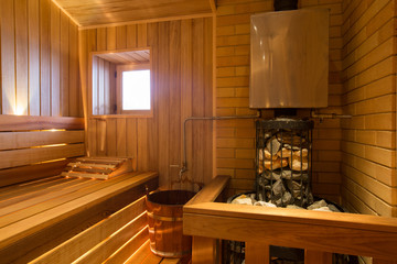 interior of relax sauna lined with wood with window, heater and stones